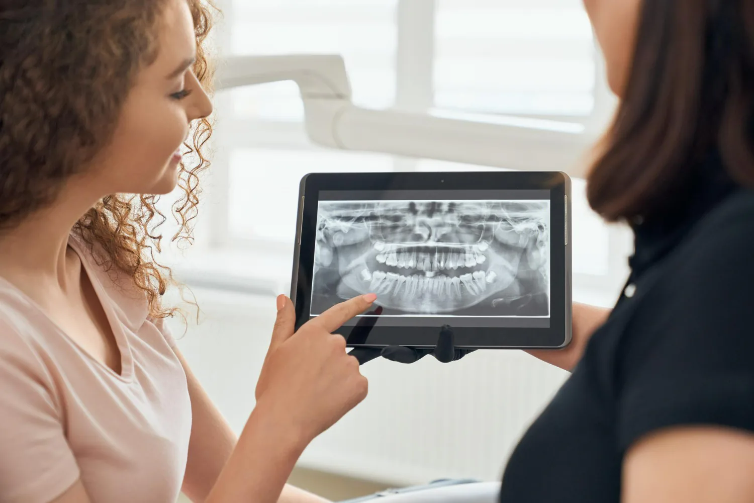 Dentist showing an X-ray of the patient’s teeth to plan their Invisalign treatment.