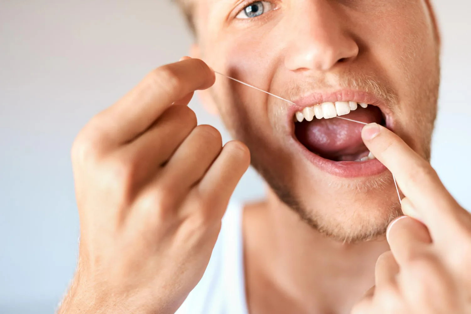 The patient is flossing their teeth to take good care of their dental bridge.