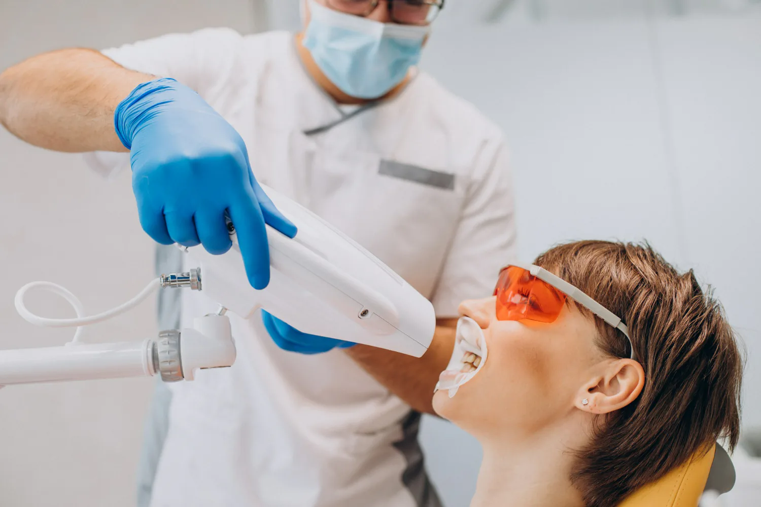 Patient receiving professional teeth whitening by the dentist.
