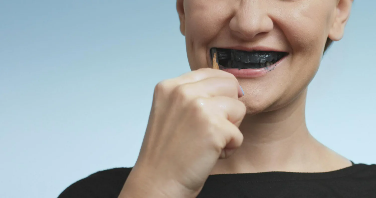 A woman using charcoal to whiten her teeth.