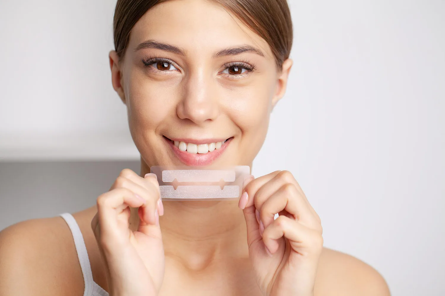 A woman using over-the-counter whitening strips.